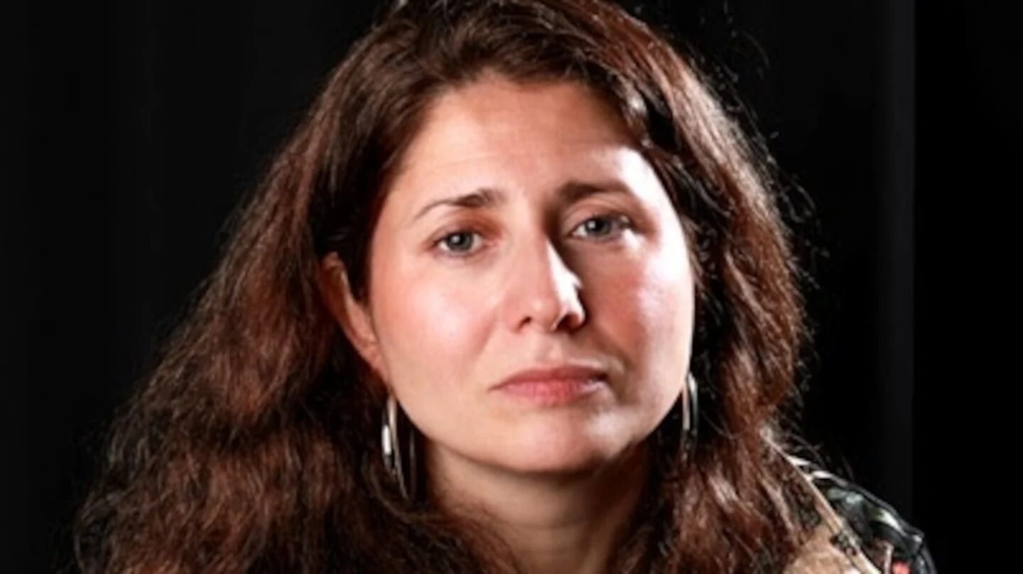Retrato de una autora argentina con cabello largo y castaño oscuro, mirando a la cámara