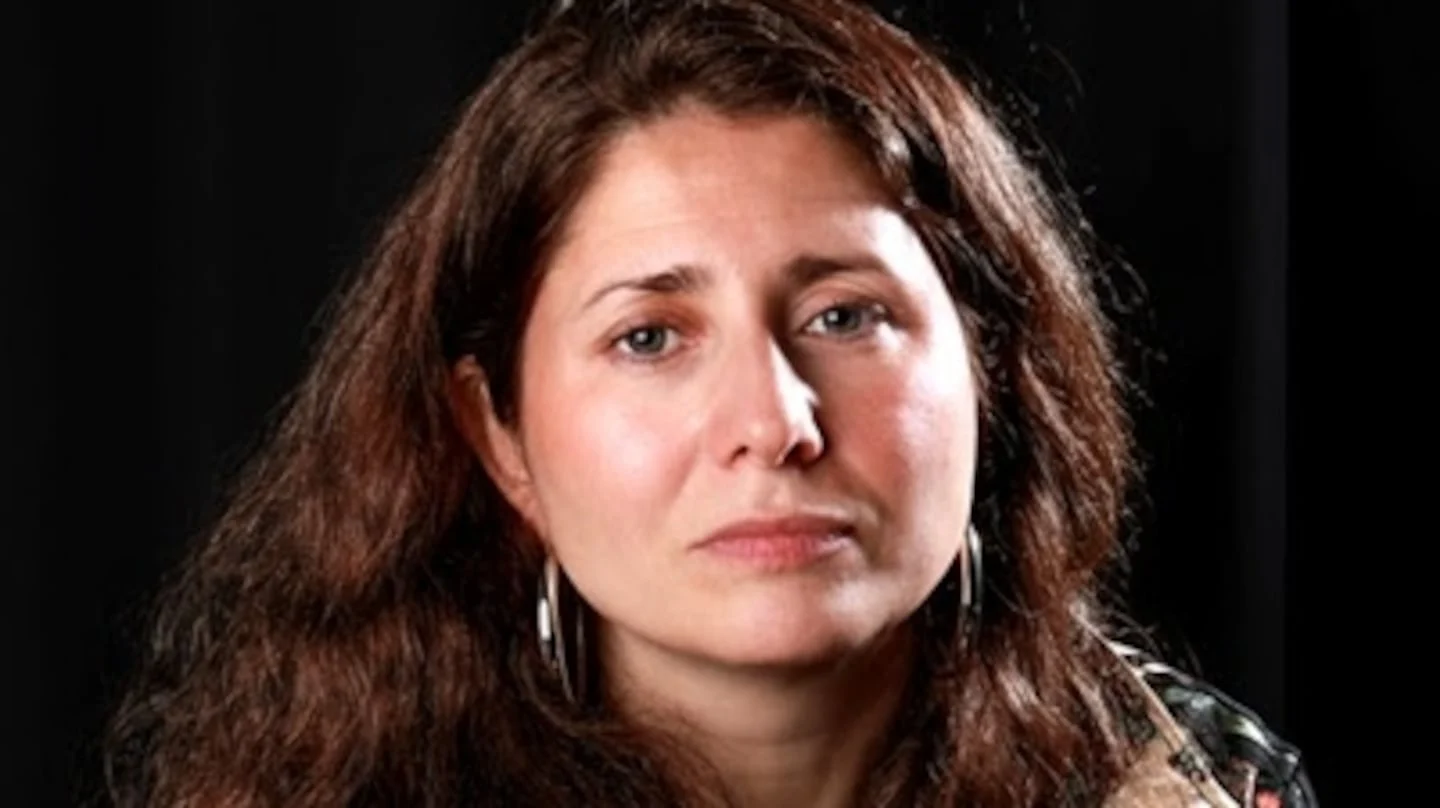 Retrato de una autora argentina con cabello largo y castaño oscuro, mirando a la cámara