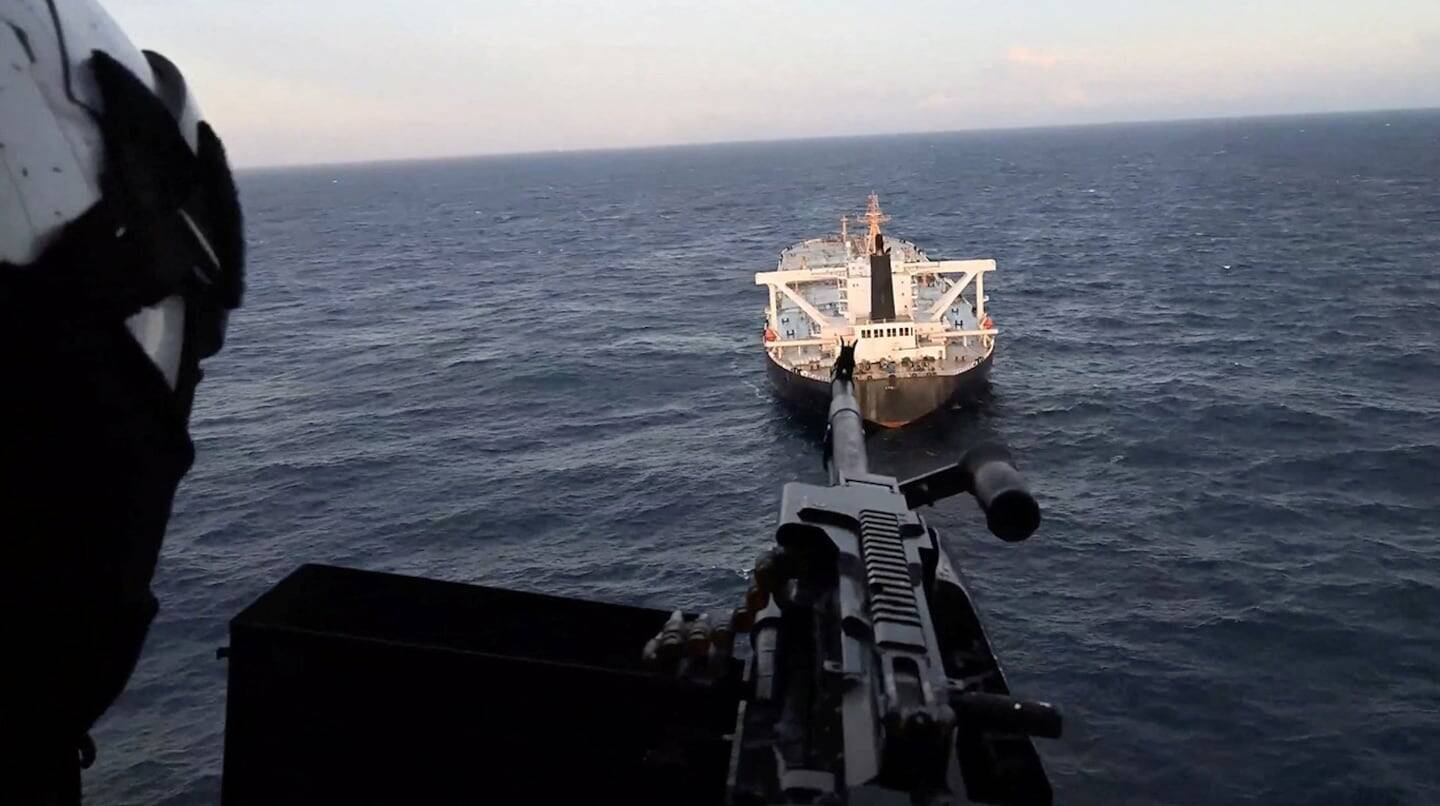 Vista de un barco en el mar con un soldado armado en primer plano