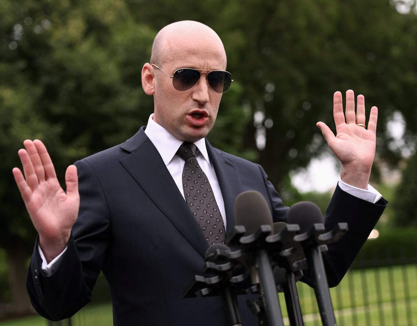 Hombre con gafas de sol y traje hablando ante micrófonos en el jardín de la Casa Blanca