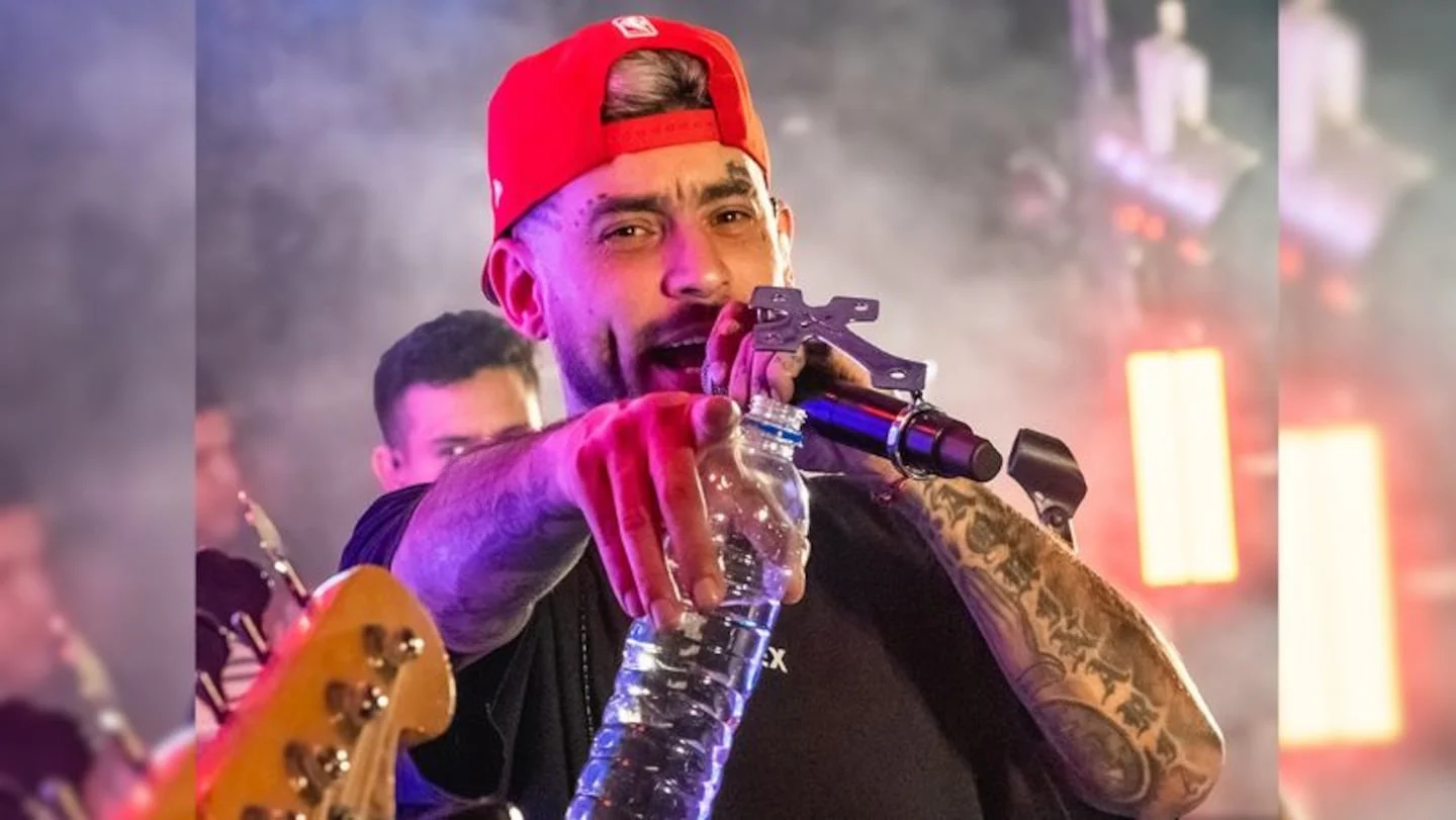 Ulises Bueno en concierto, sosteniendo una botella de agua y apuntando al público