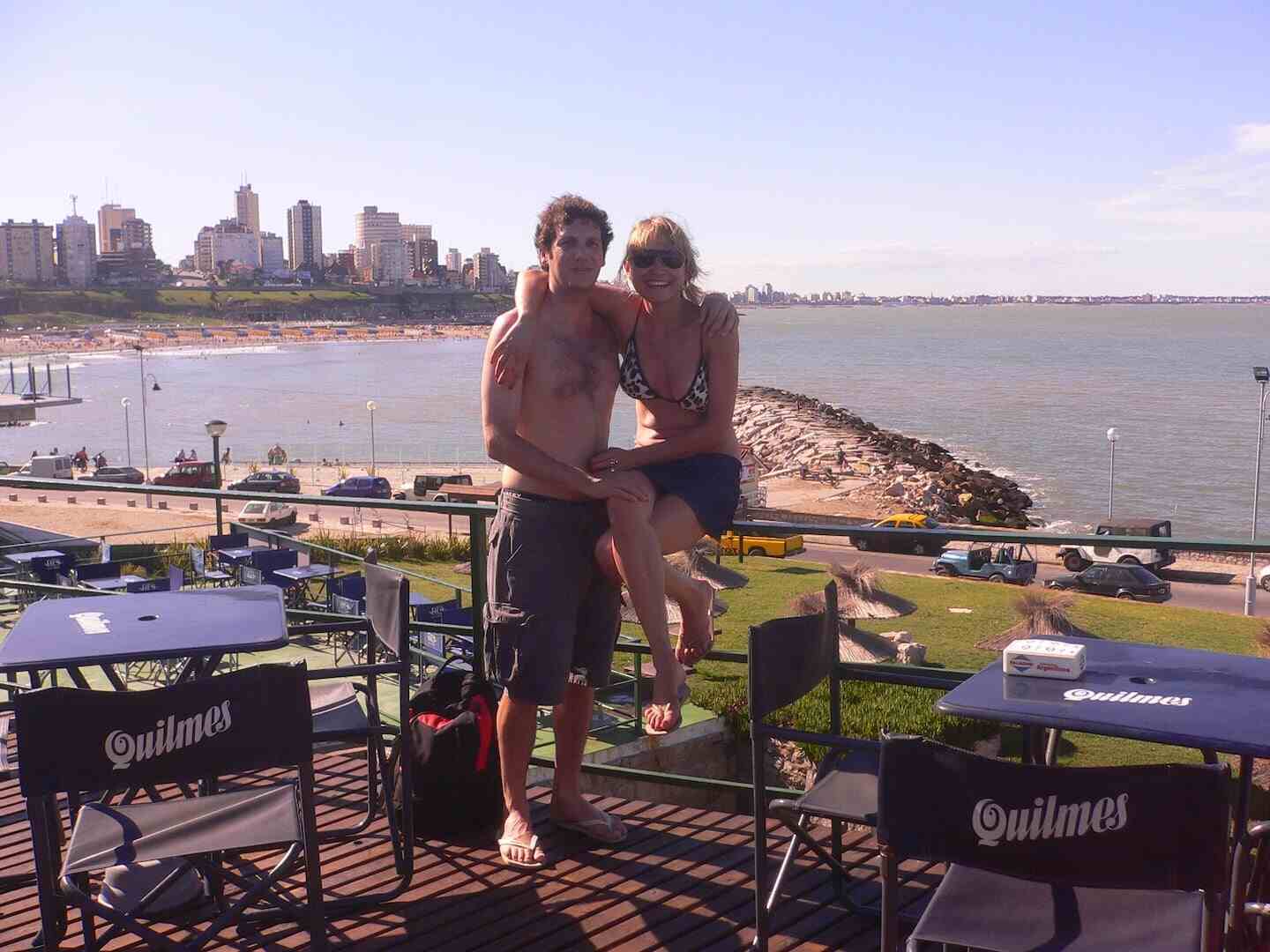Pareja sonriente en un restaurante al aire libre frente al mar
