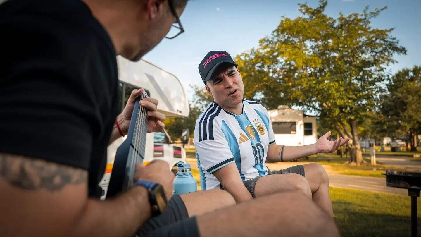 Músico argentino Santiago Meneses interpreta su canción mientras un amigo lo acompaña con una guitarra en un campamento