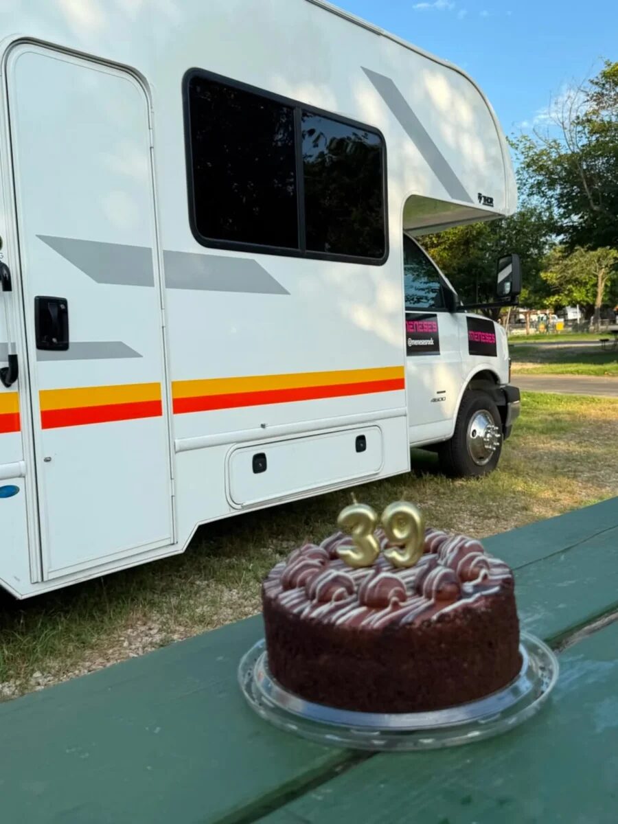 Pastel de cumpleaños con el número 39 frente a una casa rodante en un parque