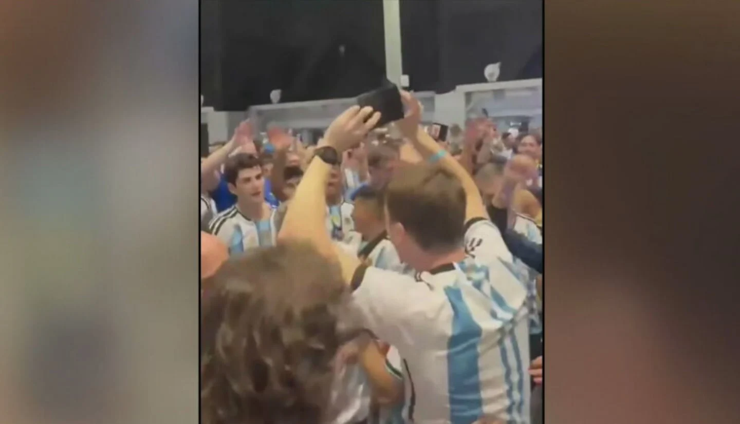 Hinchas argentinos celebran y cantan en el Mundial mientras uno sostiene una billetera