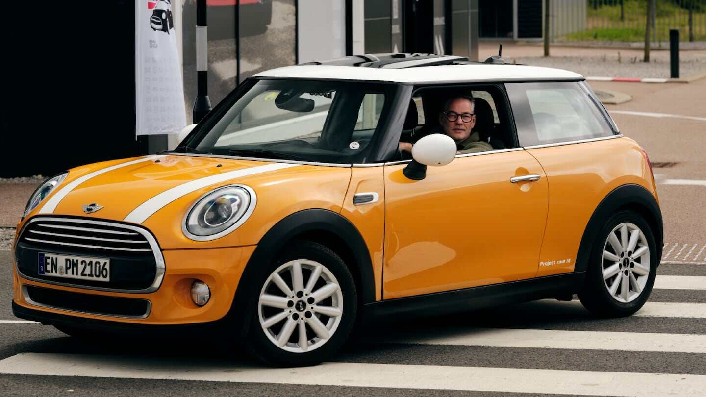 Mini Cooper D de color amarillo con techo blanco, conducido por un hombre