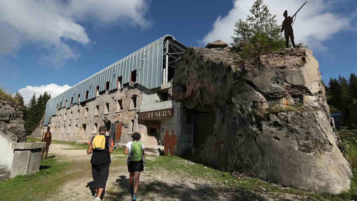 Dos personas caminando hacia un edificio en ruinas en Luserna, Italia