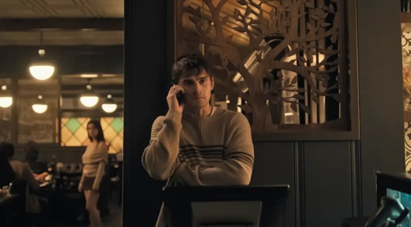 Joven en un restaurante hablando por teléfono mientras observa a una mujer al fondo