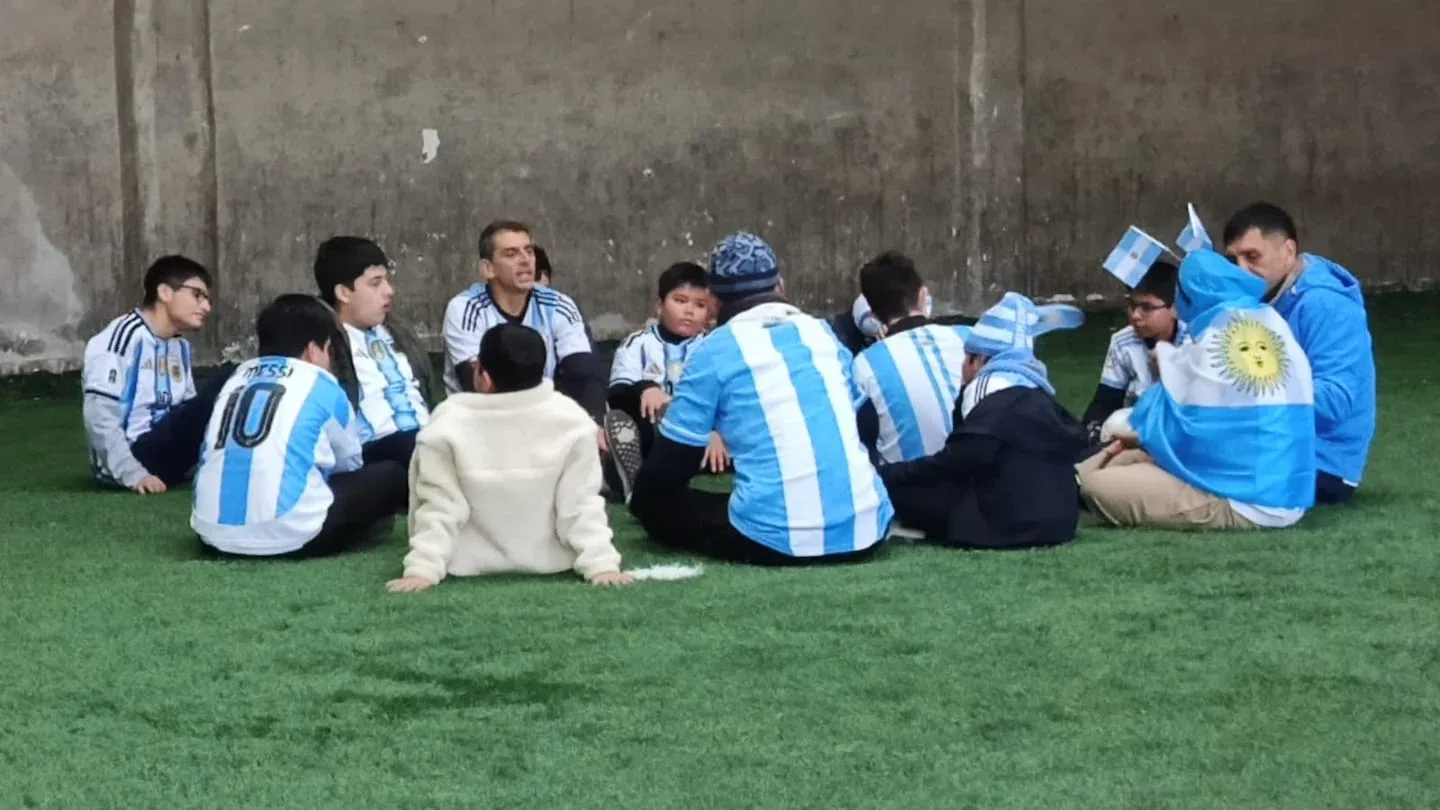 Grupo de niños con autismo en una escuela de fútbol en Jujuy, sentados en el césped