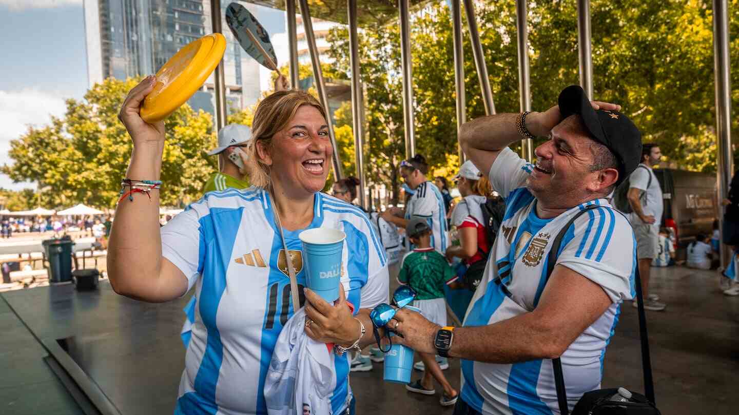 Mujer y hombre sonrientes con camisetas de la Selección Argentina en un evento del Mundial 2026