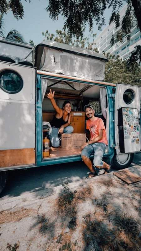Pareja argentina sonriente frente a su combi en un viaje