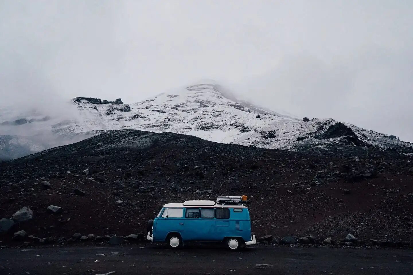 Combi azul estacionada frente a una montaña nevada