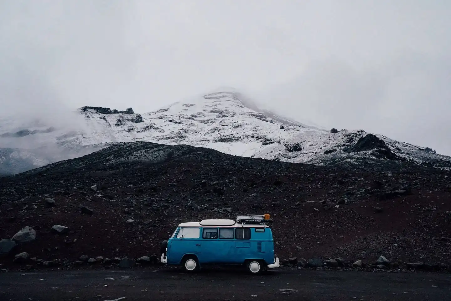 Combi azul estacionada frente a una montaña nevada