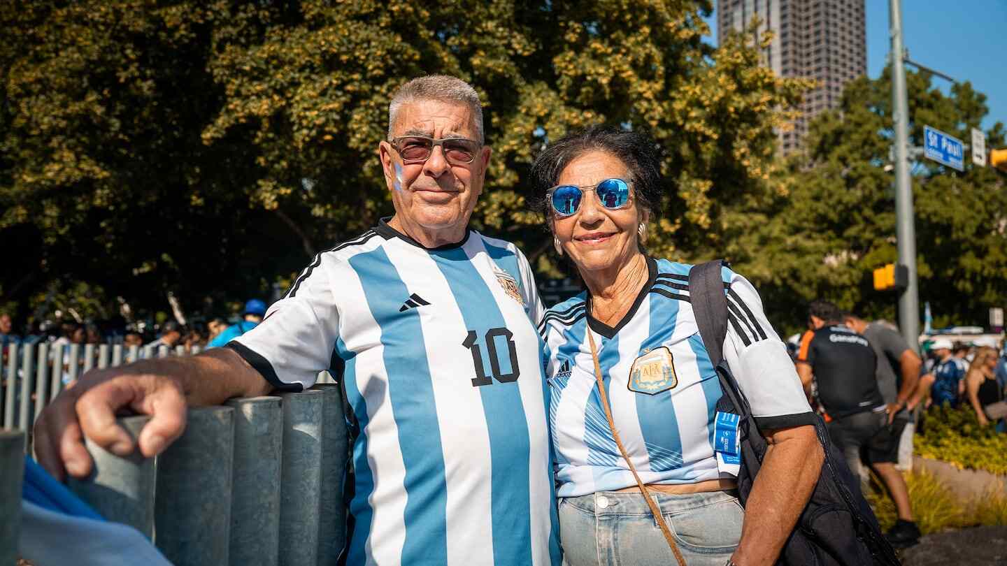 Pareja de fanáticos argentinos vestidos con camisetas de la selección de fútbol en un evento del Mundial 2026