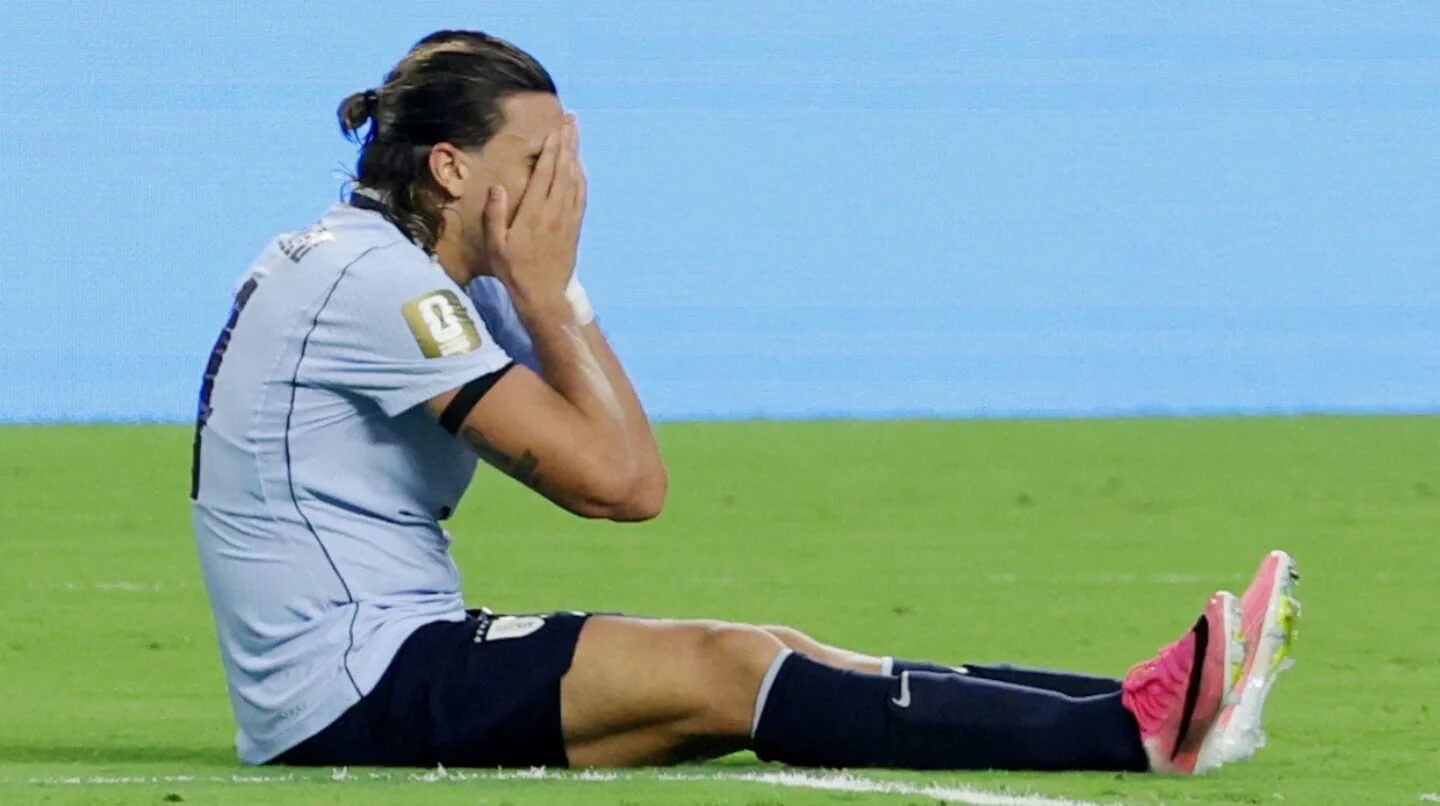 Jugador de Uruguay sentado en el campo con las manos en la cara tras una jugada fallida