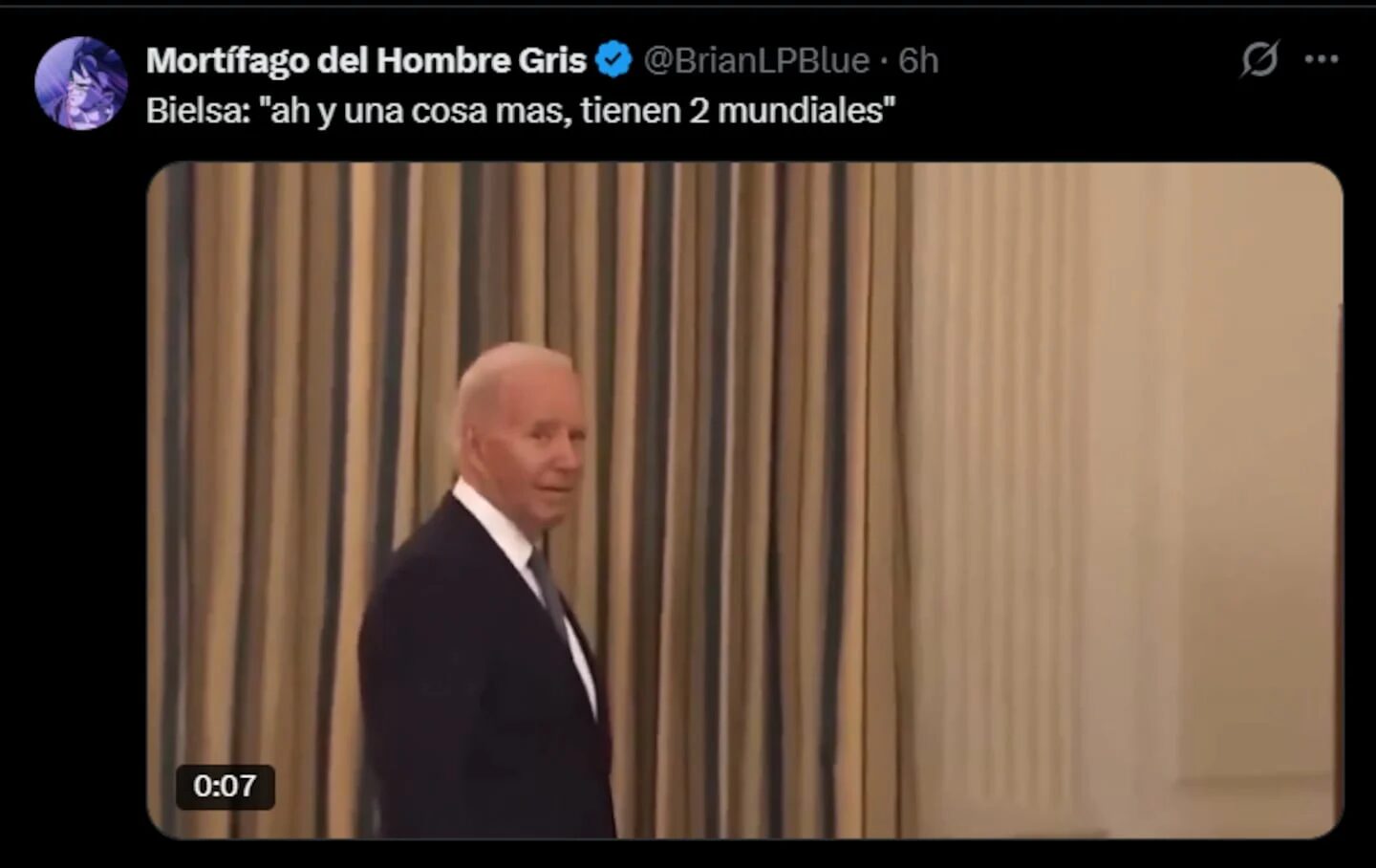 Un hombre con traje oscuro camina frente a una cortina con rayas en un entorno formal