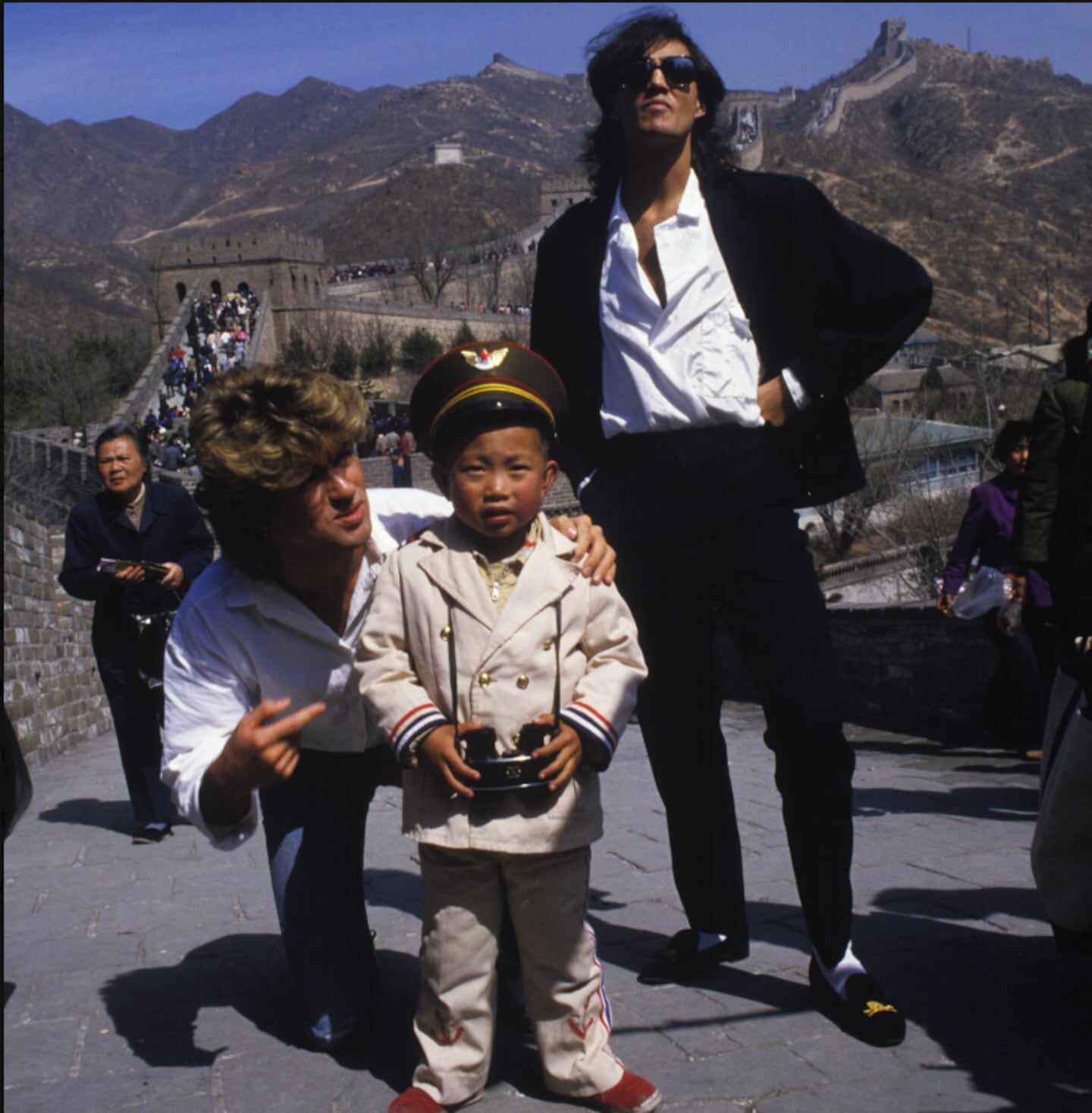 George Michael y Andrew Ridgeley de Wham! posan con un niño en la Gran Muralla China