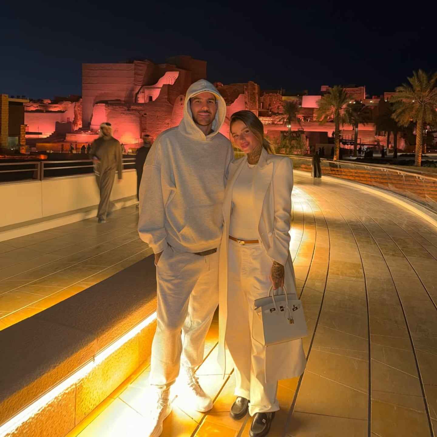 Zoe Cristofoli y Theo Hernández posando en un entorno iluminado por la noche