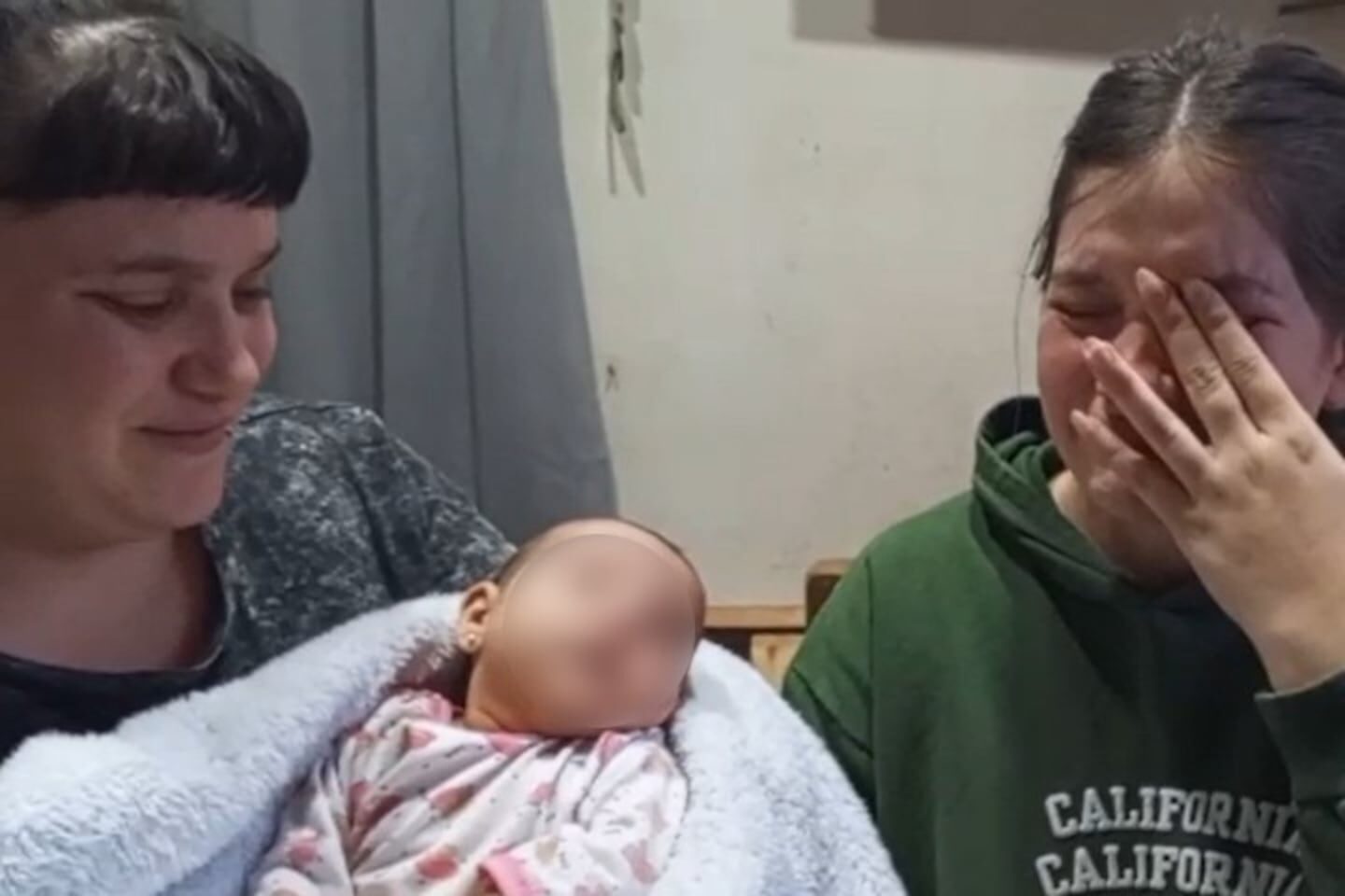 Dos mujeres sosteniendo a una bebé envuelta en una manta en Coronel Pringles