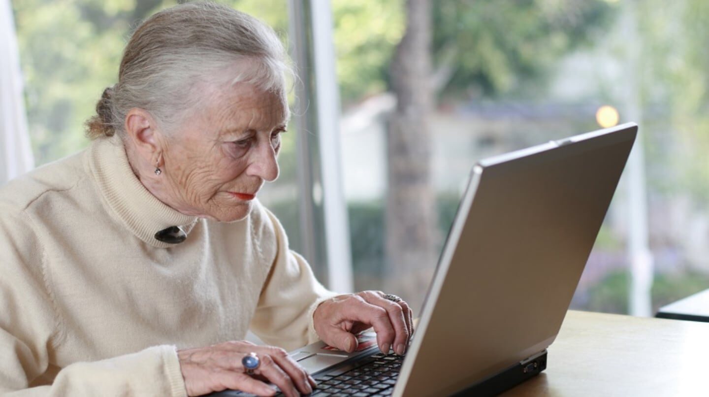 Mujer mayor usando una computadora portátil en un entorno luminoso