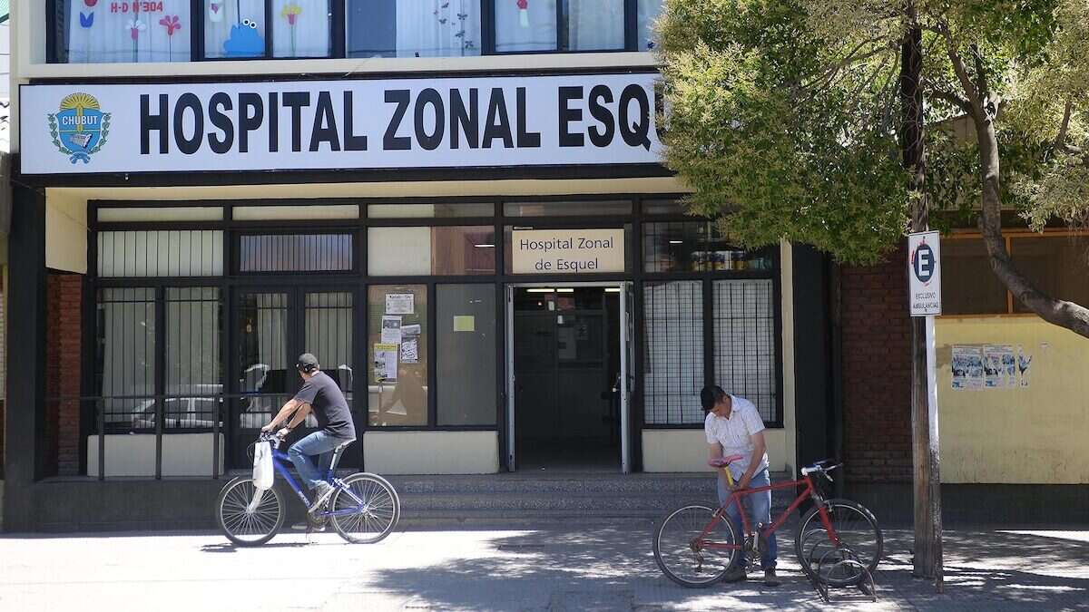 Fachada del Hospital Zonal de Esquel con dos personas en bicicleta frente a la entrada
