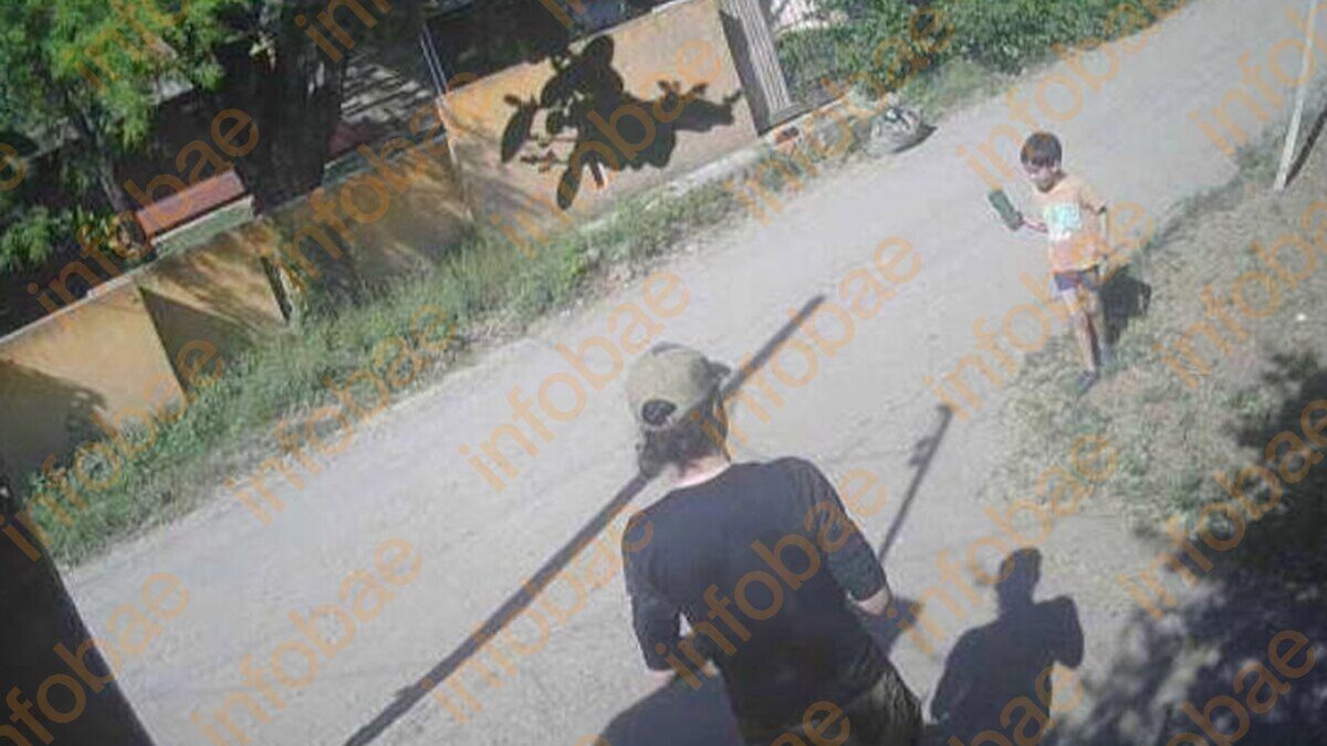 Hombre con un palo en una calle mientras un niño observa