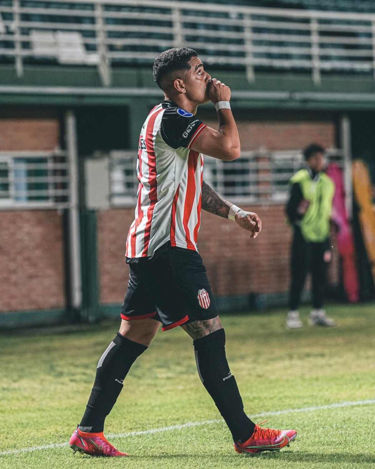 Gonzalo Morales caminando en el campo de juego con gesto de silencio