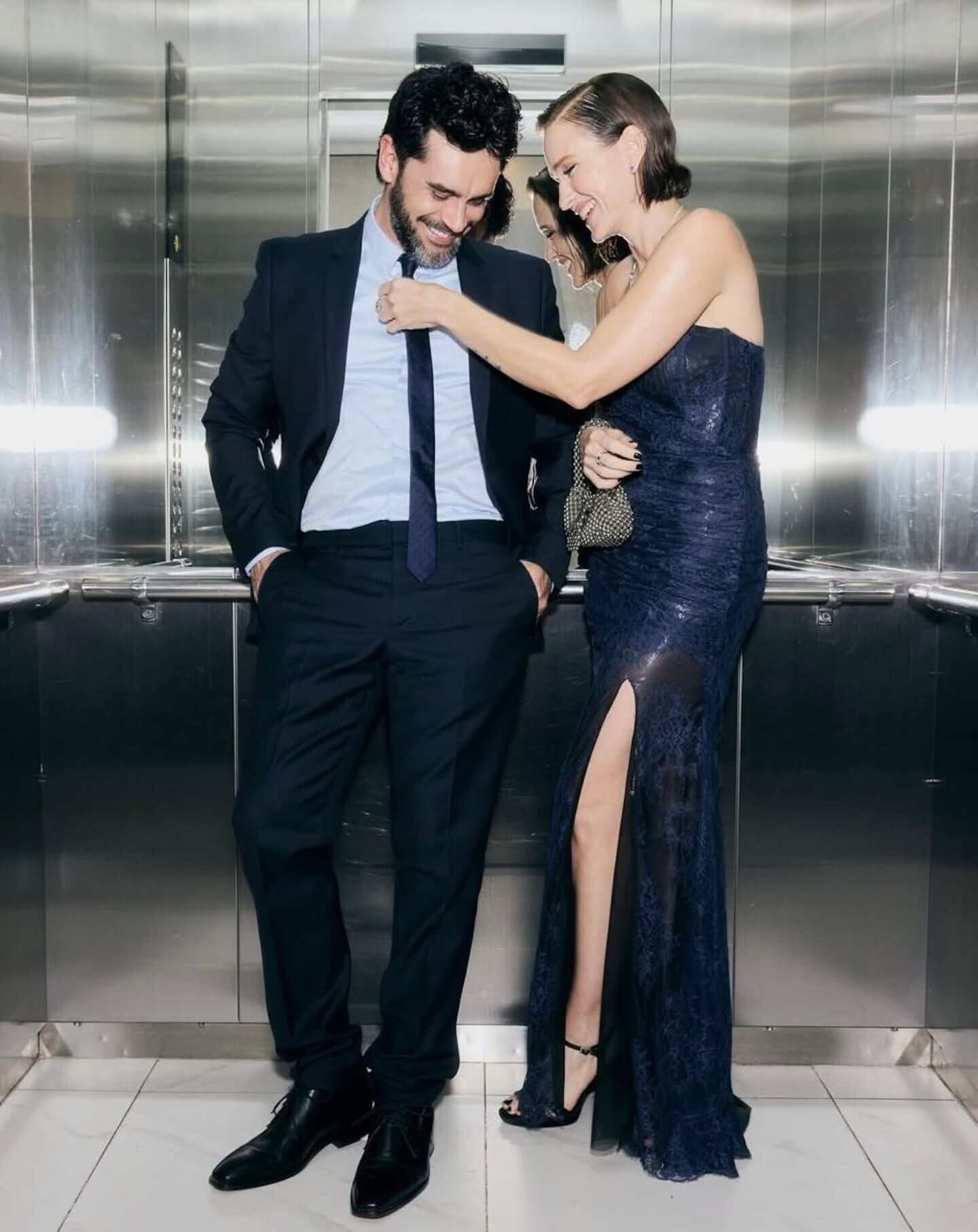 Brenda Gandini y Gonzalo Heredia posando en un ascensor con elegantes trajes azules