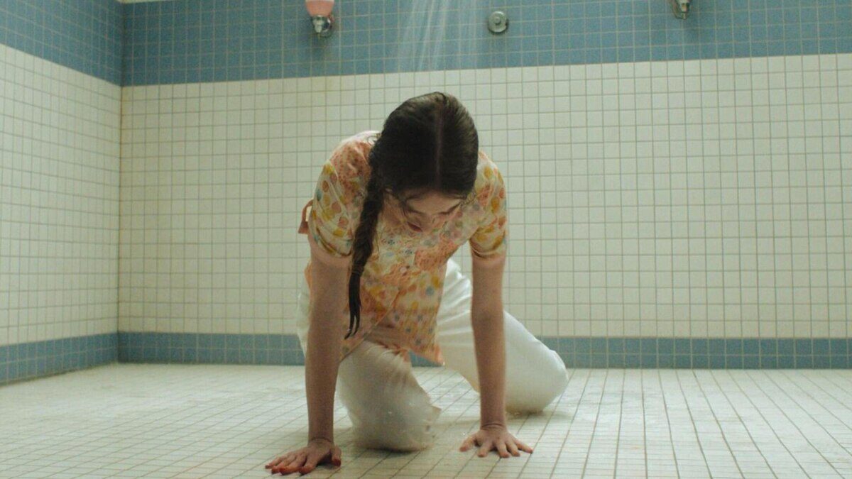 Escena de la miniserie Carrie donde una joven se encuentra en el suelo de un baño, visiblemente angustiada