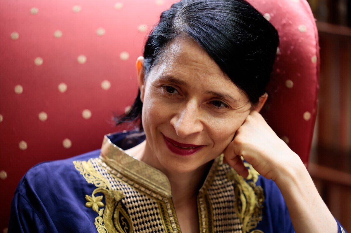 Chloe Aridjis, escritora mexicano-estadounidense, sonriendo en un sillón rojo