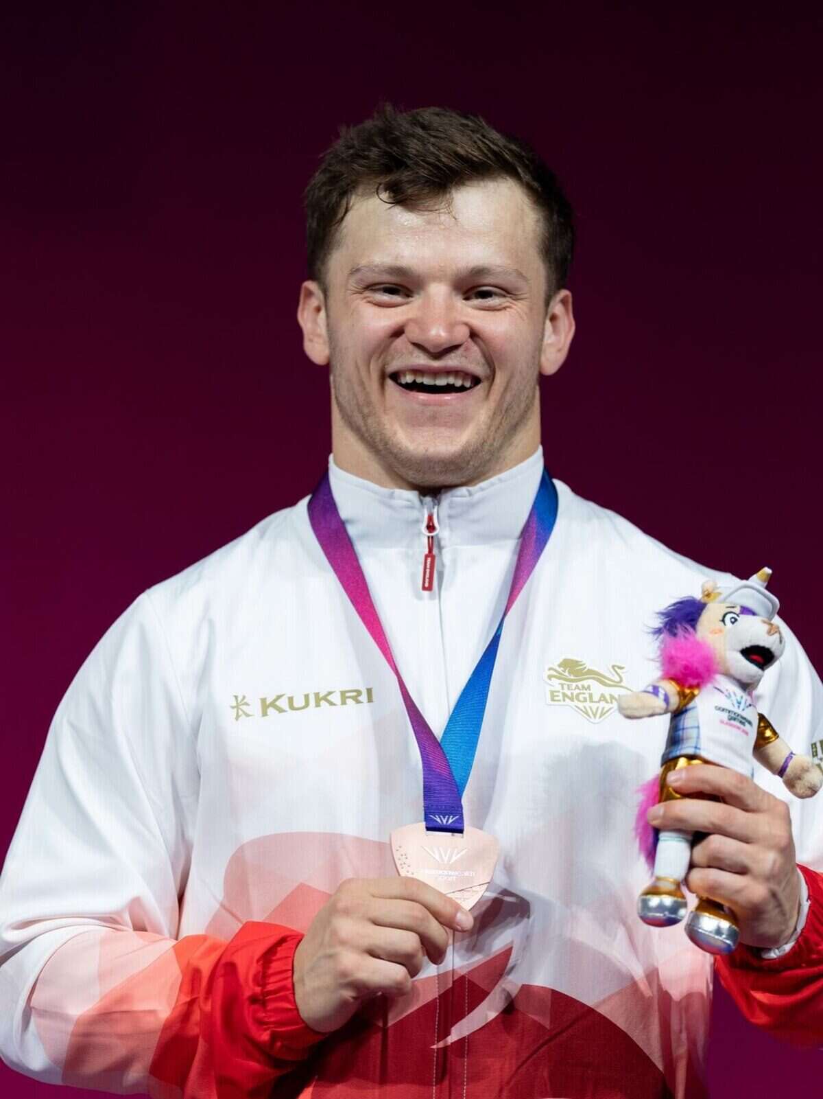 Chris Murray sonríe sosteniendo su medalla de bronce y un muñeco en los Juegos de la Commonwealth