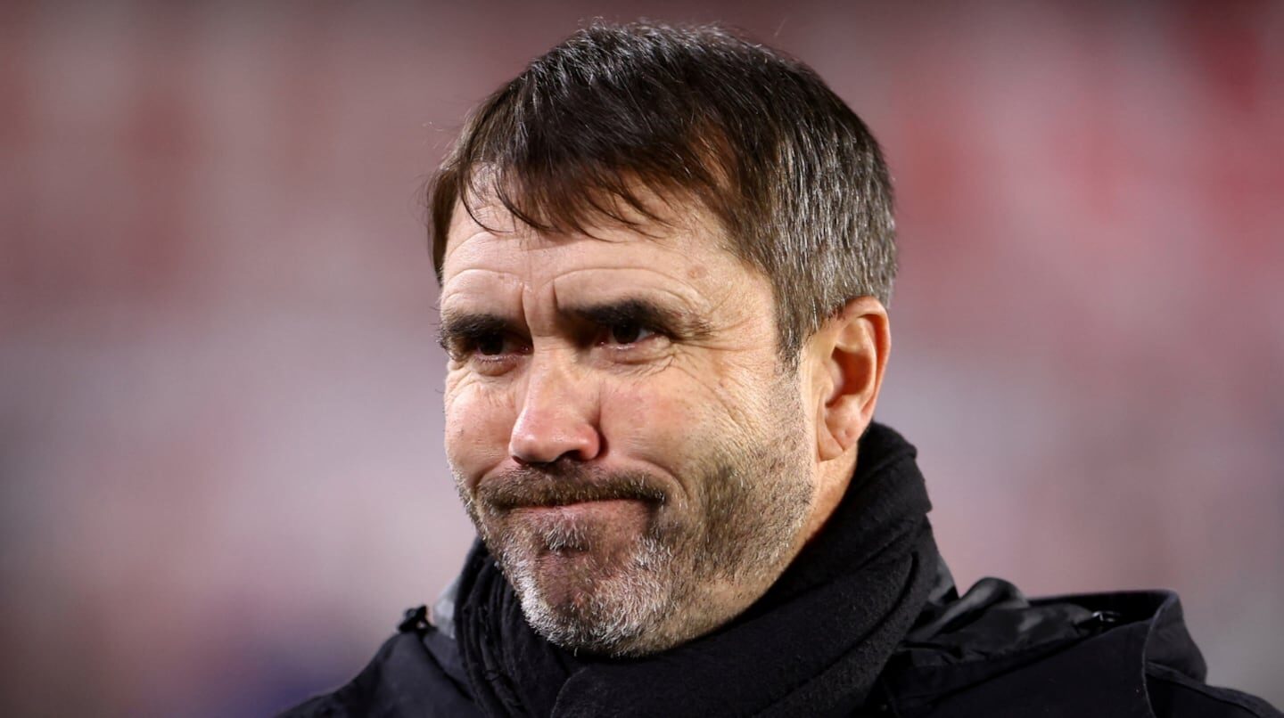 Entrenador de fútbol con expresión reflexiva durante un partido