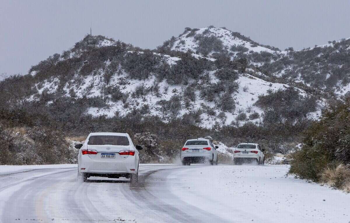 Tres vehículos circulando por una carretera nevada en la cordillera argentina