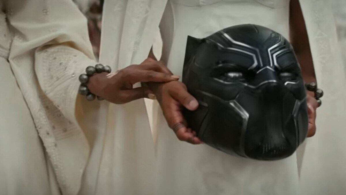 Máscara de Black Panther sostenida por manos en un entorno ceremonial