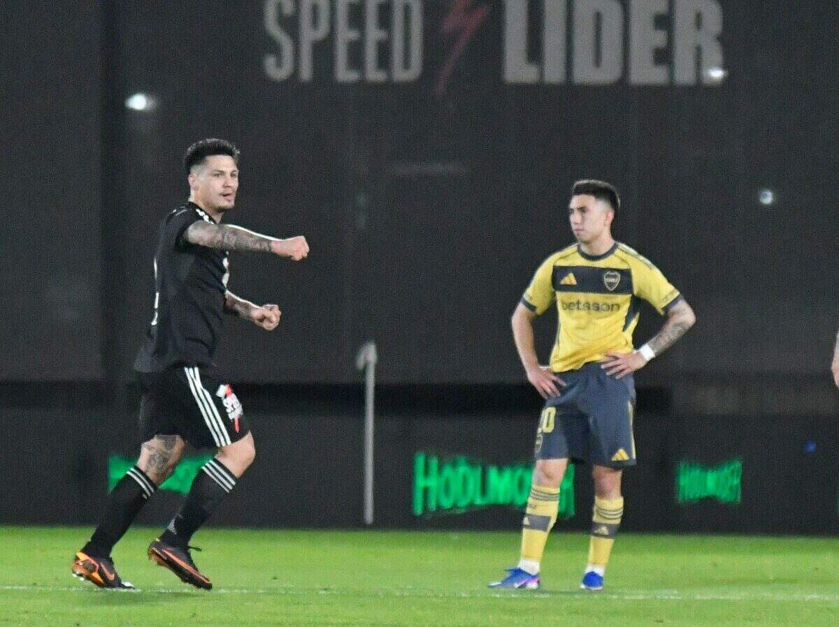 Jugador de Deportivo Riestra celebra un gol mientras un jugador de Boca Juniors observa