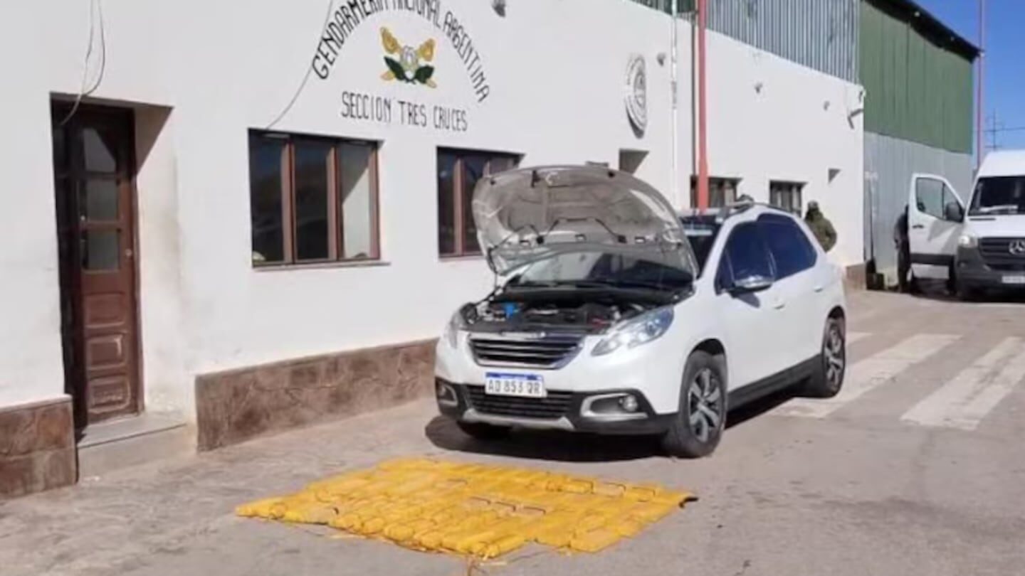 Vehículo blanco con el capó abierto y paquetes de cocaína en el suelo durante un operativo de la Gendarmería Nacional en Jujuy