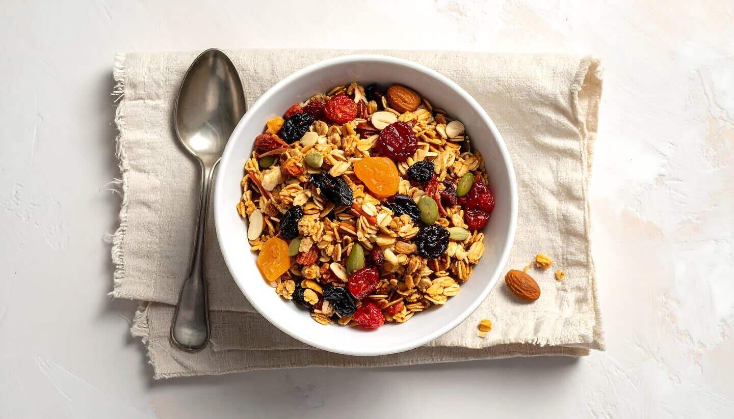 Tazón de granola con frutas secas y frutos secos sobre una servilleta clara
