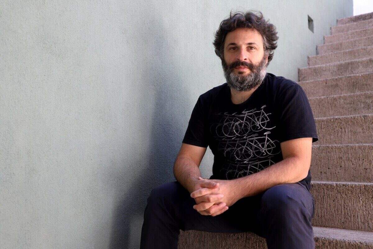Hombre sentado en una escalera con camiseta negra y barba