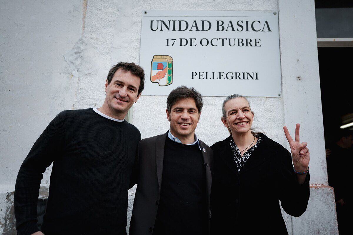 Tres políticos argentinos posan frente a un cartel de la Unidad Básica 17 de Octubre en Pellegrini
