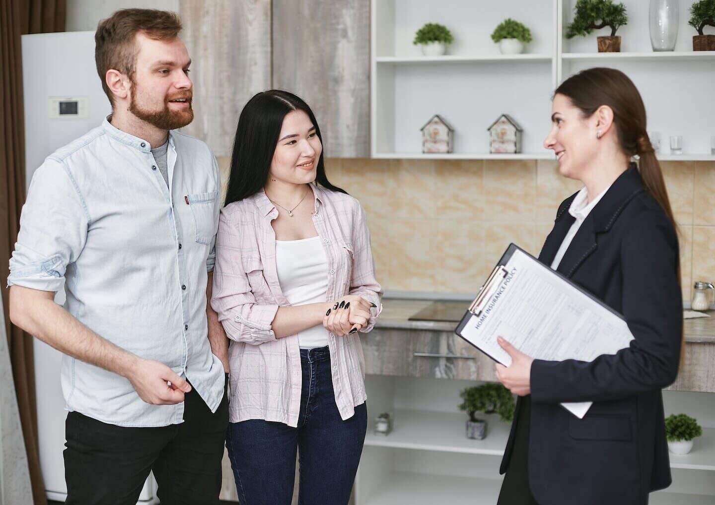 Pareja joven conversando con una agente inmobiliaria en una oficina