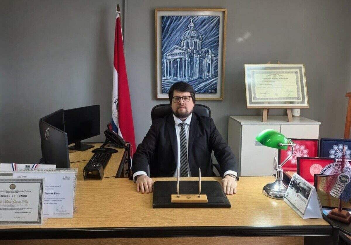 El juez Matías Garcete Piris en su oficina, con documentos y una bandera de Paraguay de fondo