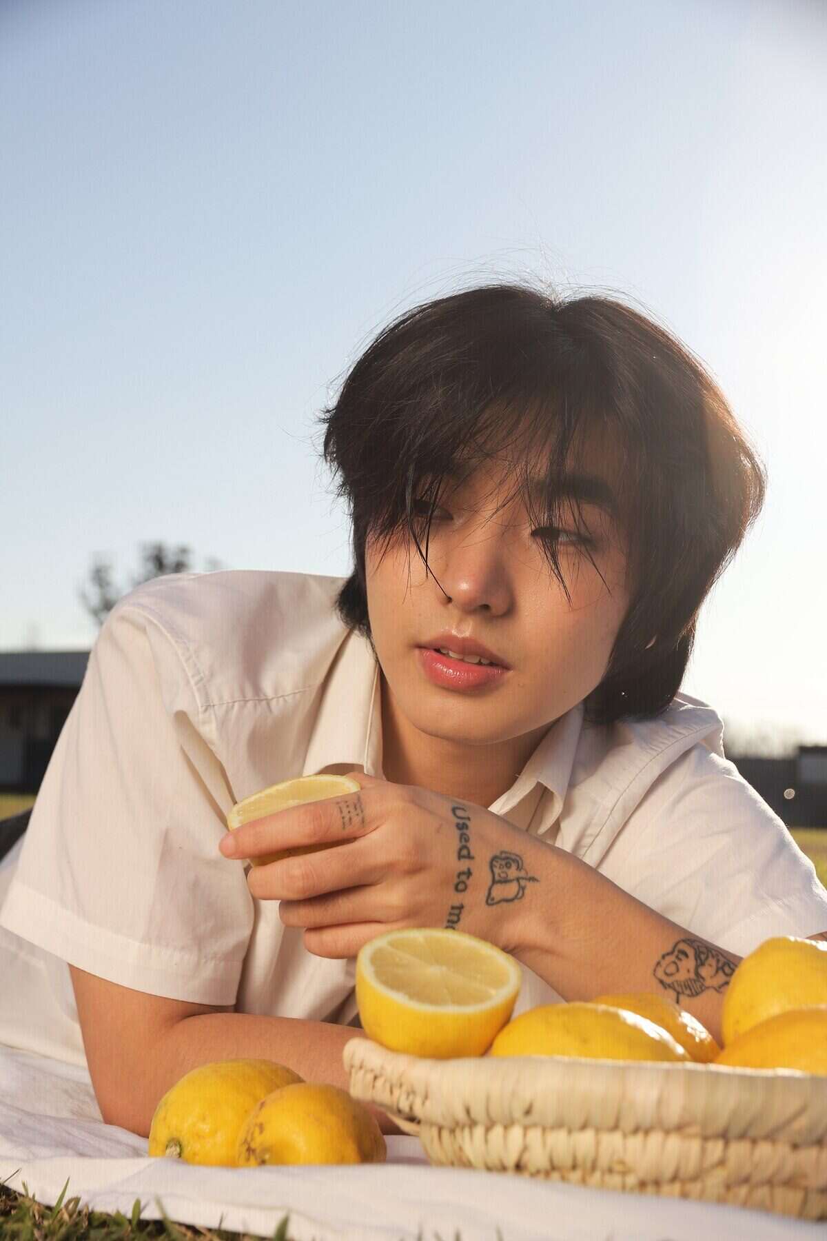 Jin Min Lee sosteniendo un limón con una canasta de limones en el campo