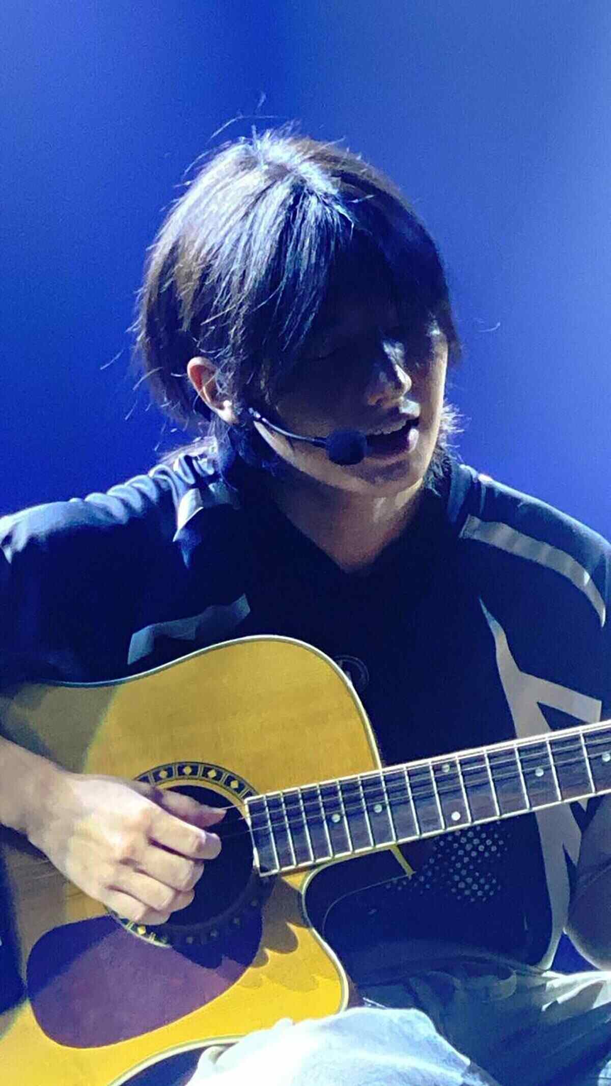 Jin Min Lee tocando la guitarra en un escenario con luz azul