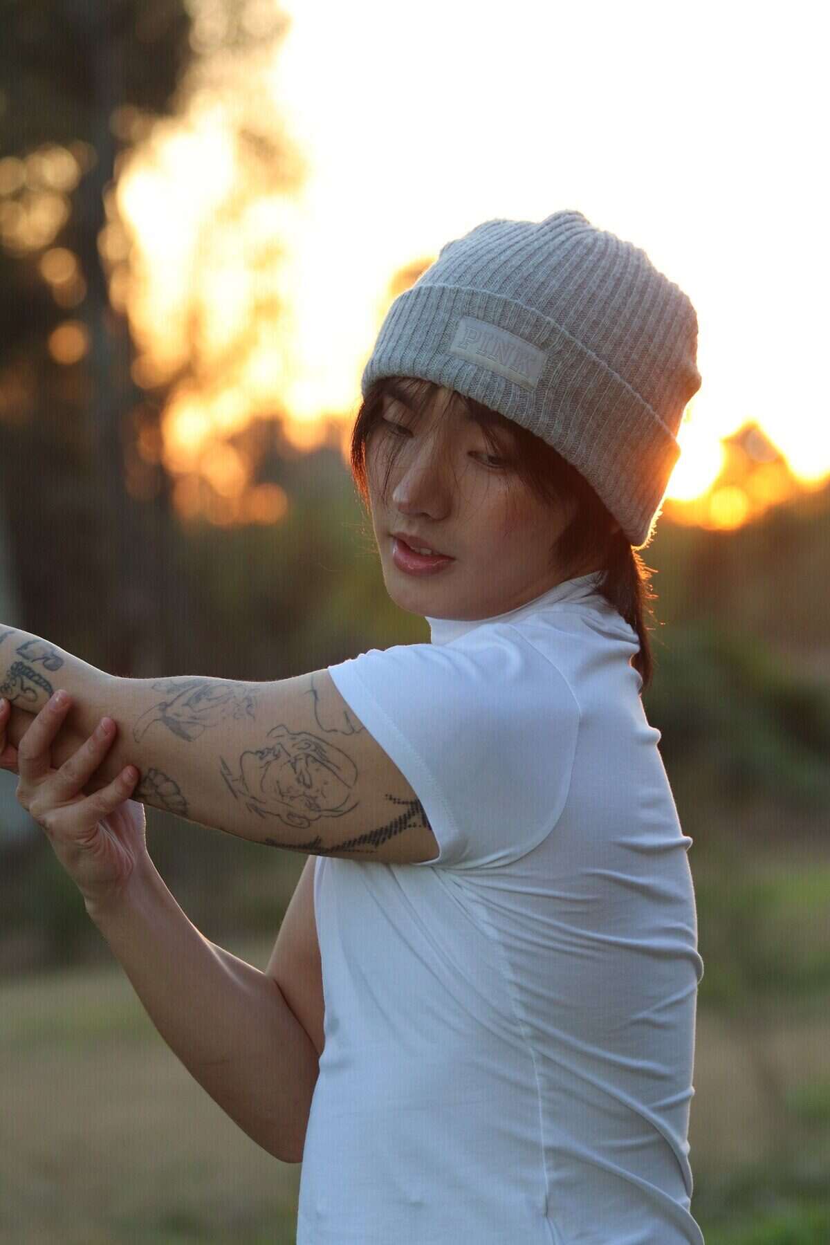 Jin Min Lee ajustándose la camiseta al atardecer en un entorno natural