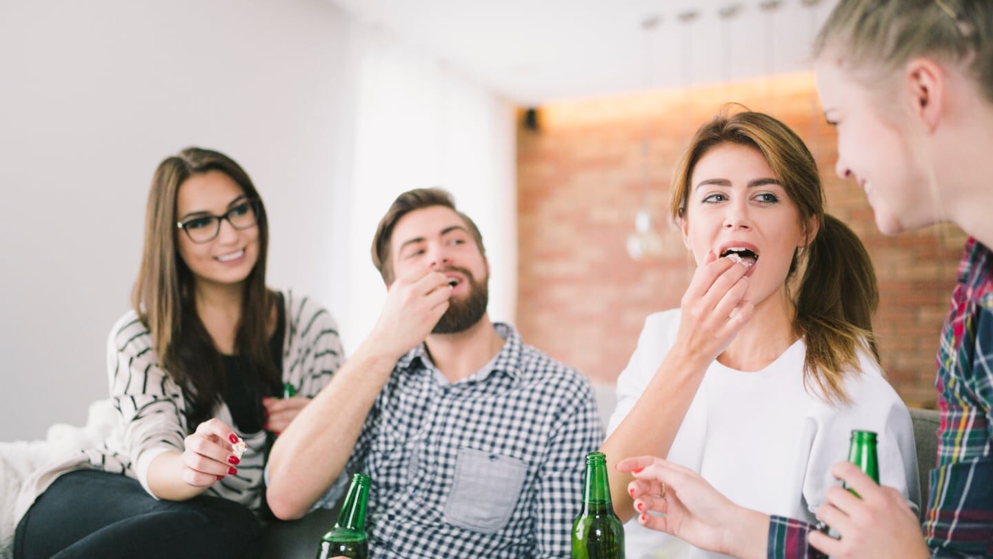Grupo de amigos compartiendo y riendo en un ambiente informal con bebidas