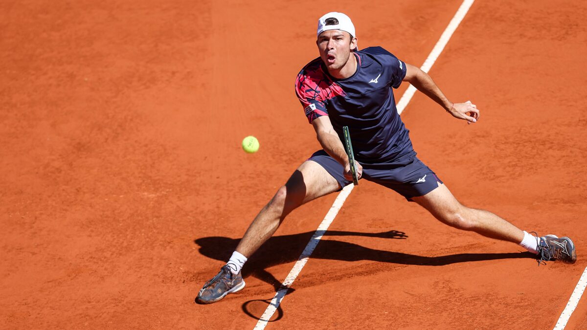 Jugador argentino de tenis realizando un golpe en una cancha de arcilla