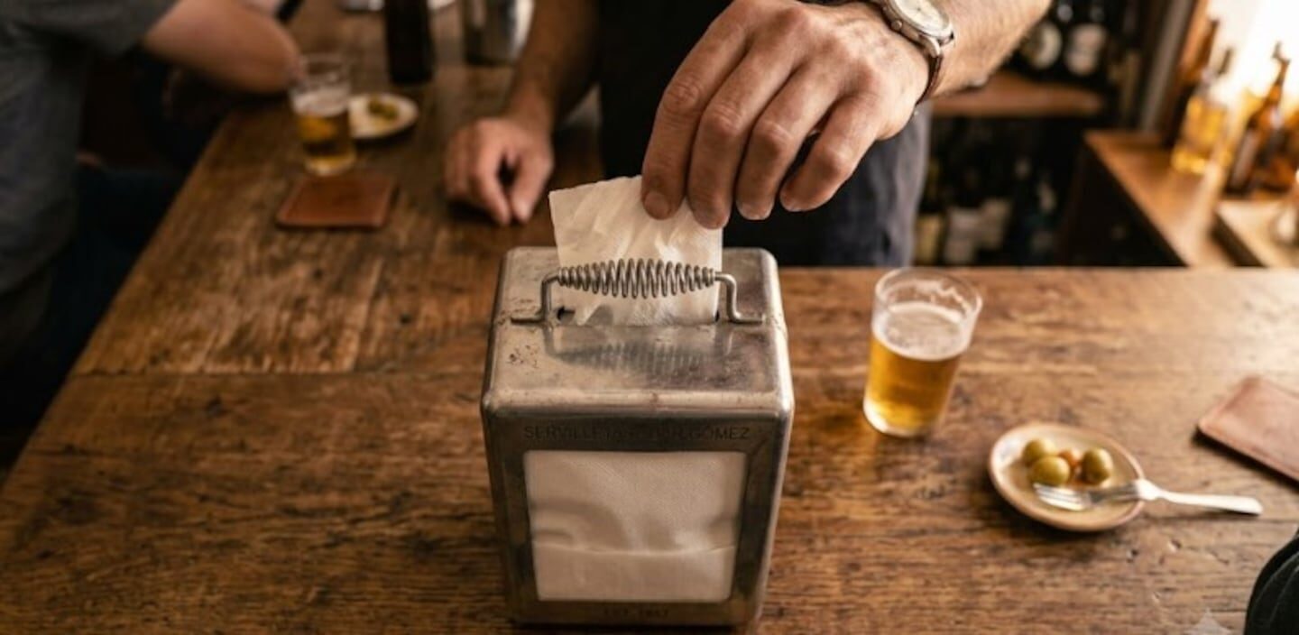 Un hombre colocando una servilleta en un dispensador de bar en Argentina