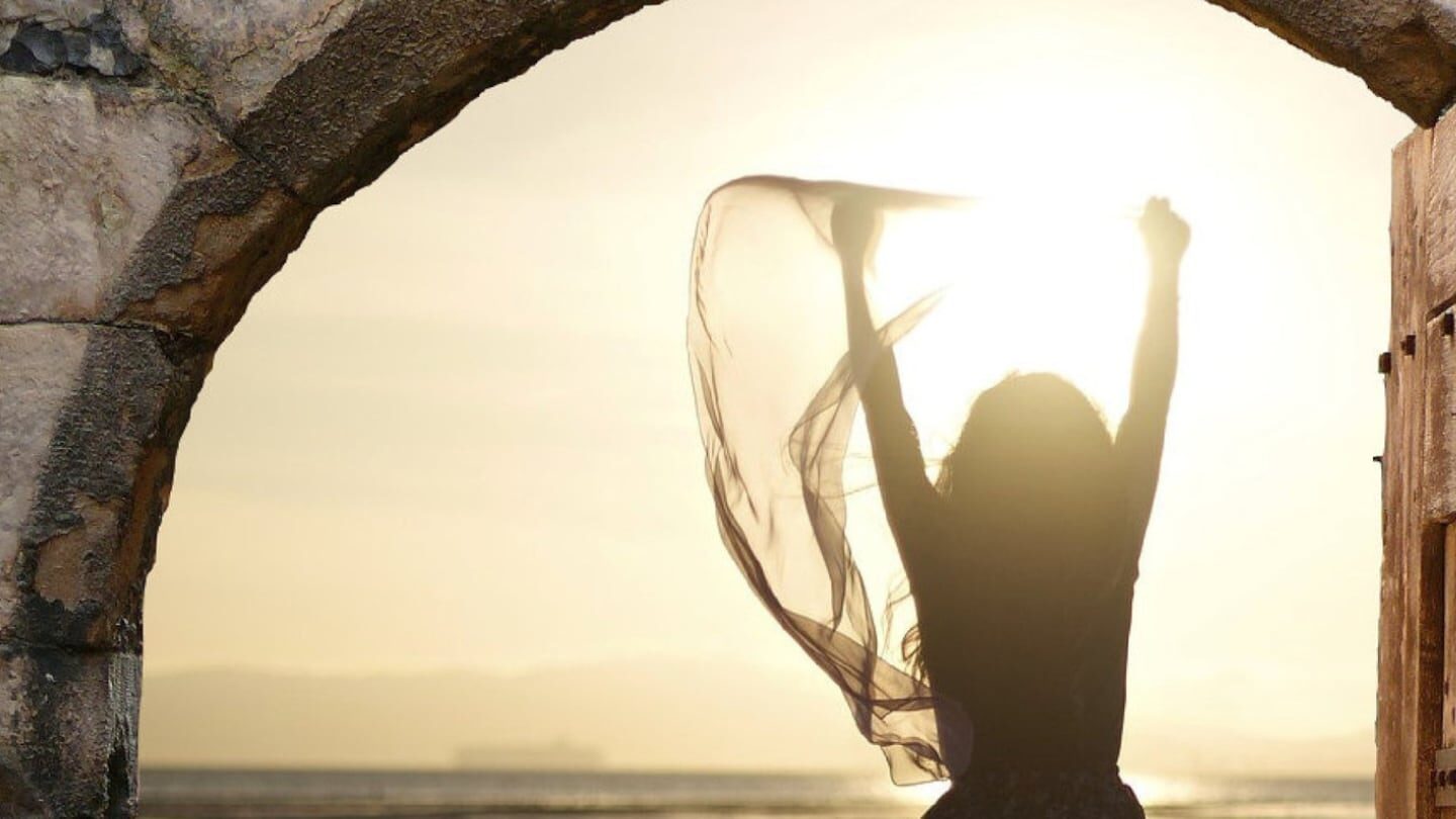 Silhouette de una persona levantando los brazos al atardecer con un pañuelo en la mano