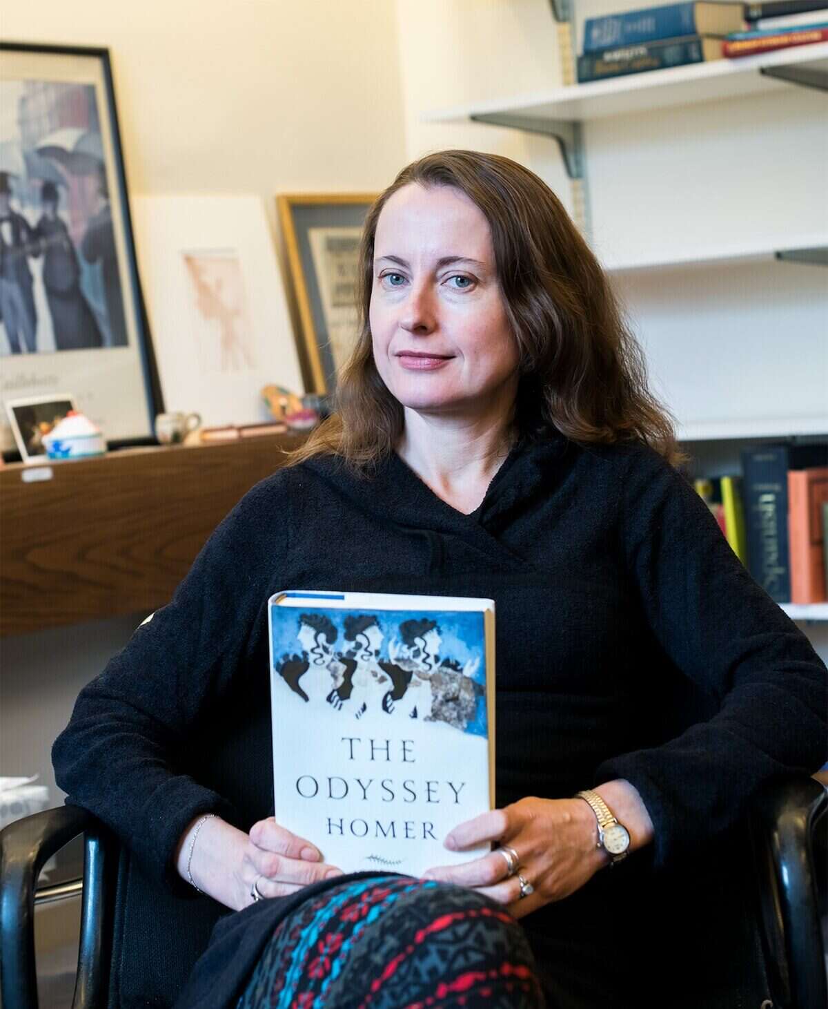 Emily Wilson sosteniendo un libro de 'La Odisea' de Homero en su oficina