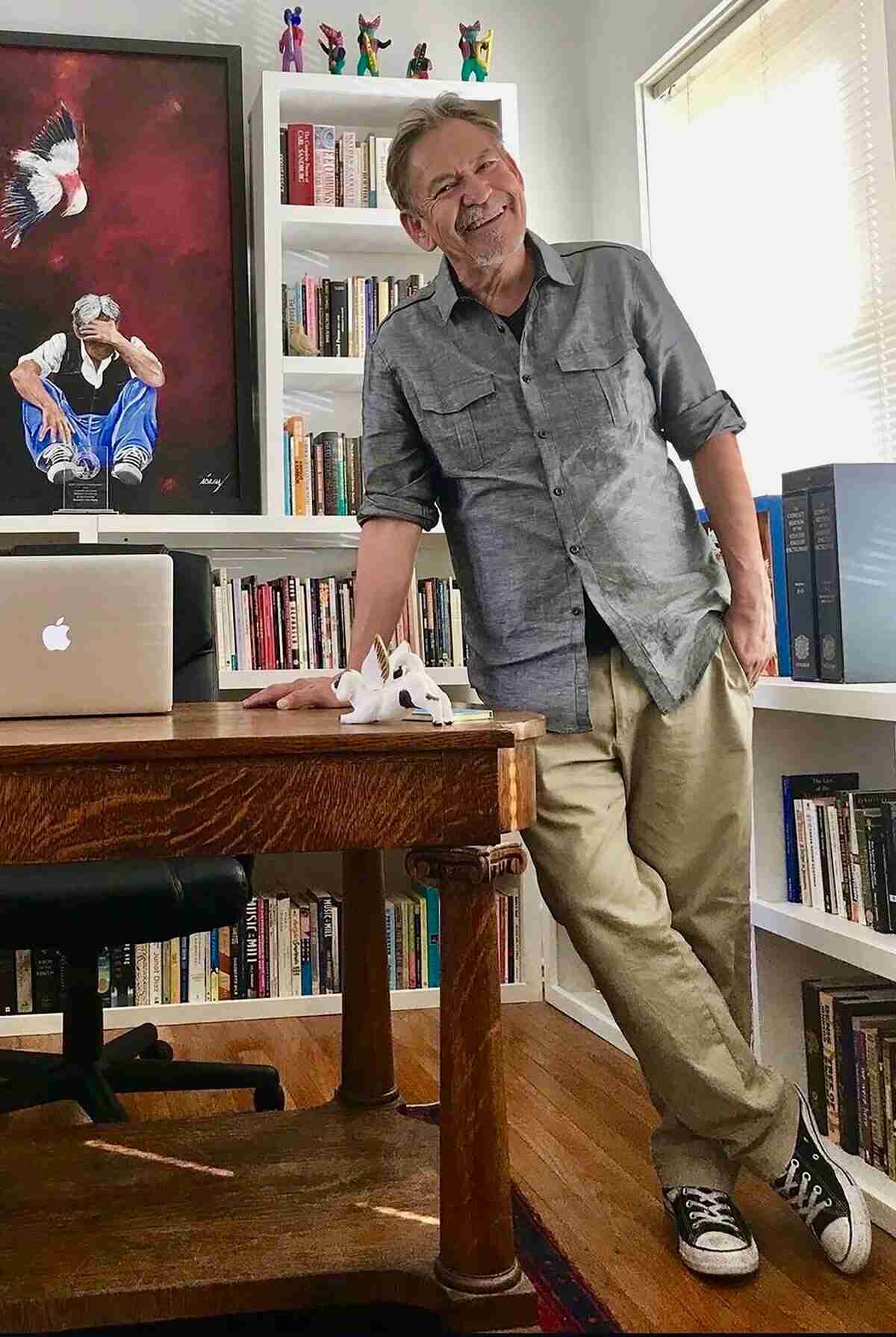 Benjamin Alire Sáenz posando en su estudio junto a una mesa de trabajo